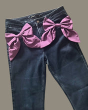 Load image into Gallery viewer, Dark blue jeans styled with two purple silk statement bow brooches pinned at the hips.