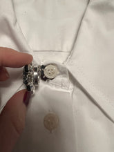 Load image into Gallery viewer, Black and clear diamonte single button cover being clipped over top of a shirt button