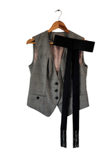 Load image into Gallery viewer, A gray plaid tailored vest with a black wide bow pinned on lapel hanging on a wooden hanger against a white background.
