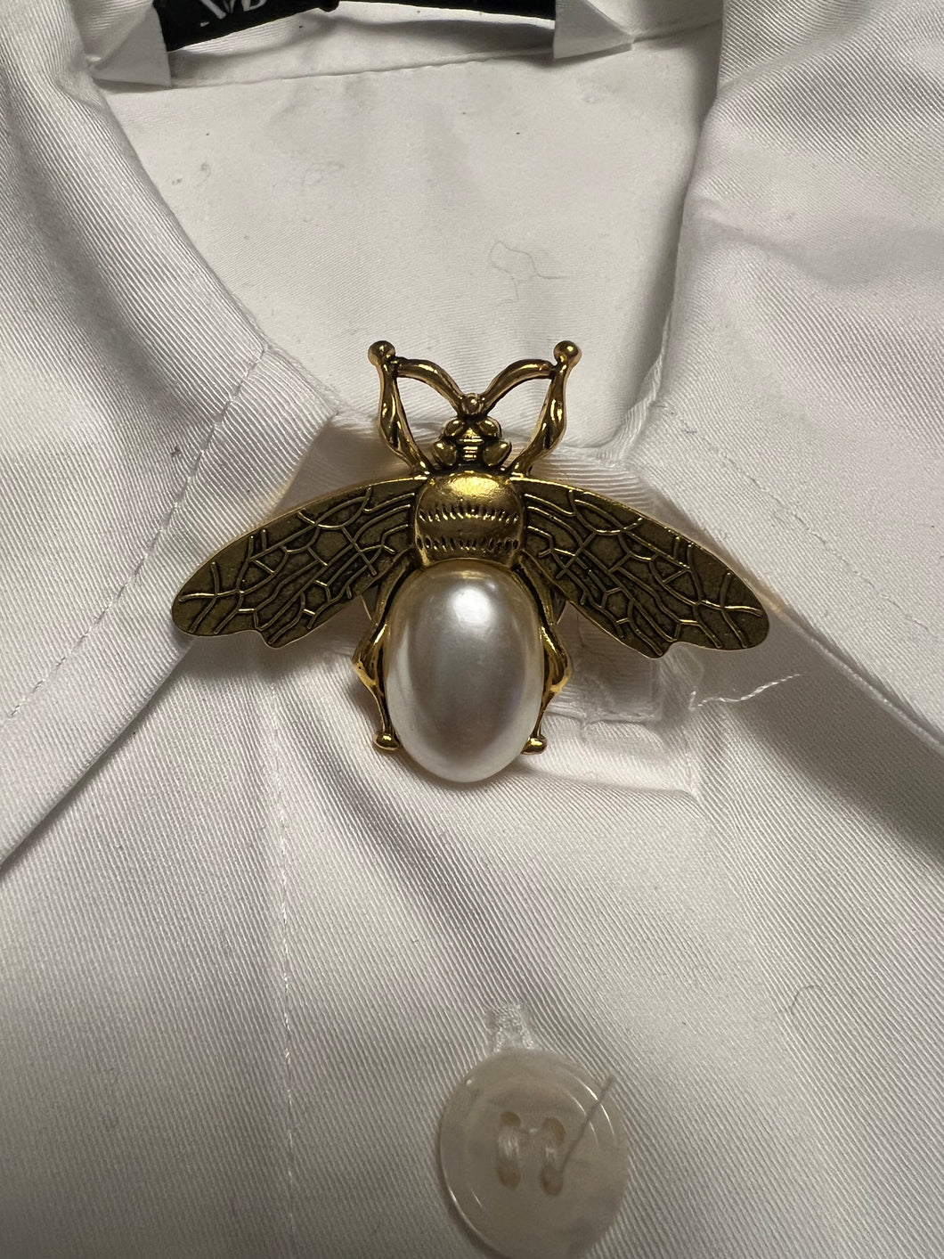 Gold and pearl bee shaped button cover on top button of shirt